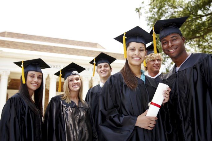 Grupo de graduados sonrientes con birretes y diplomas al aire en un entorno académico.