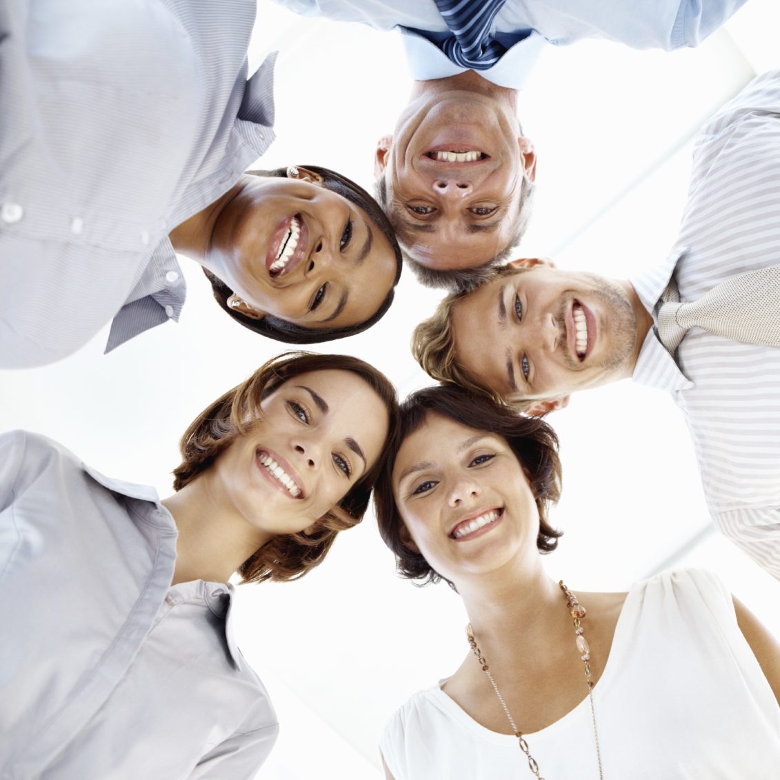 Grupo de cinco personas sonriendo, formando un círculo desde abajo.